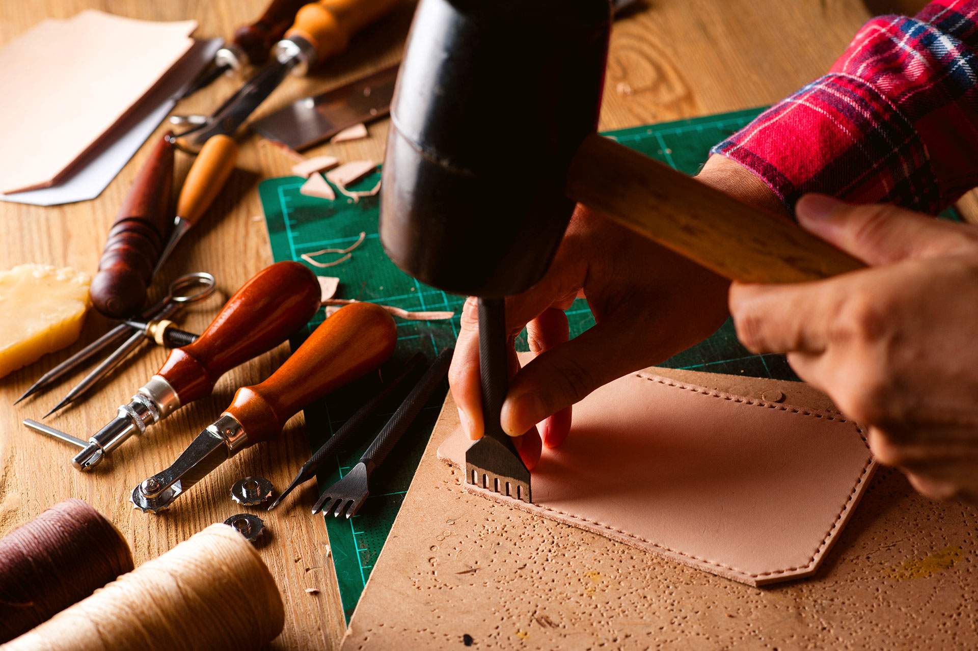 Leatherworker using mallet and chisel to punch holes