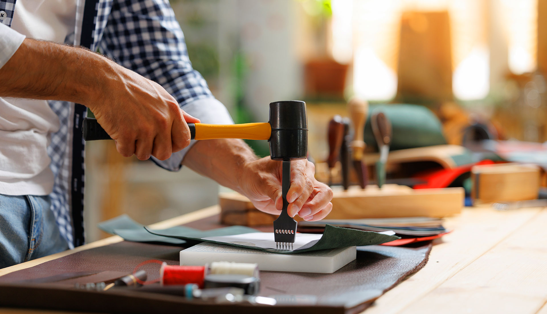 Craftsman using mallet and prong tool on leather